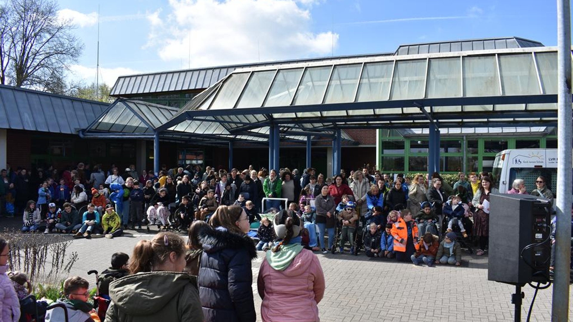 [Aus Metadaten]Blick auf die Schüler und Mitarbeiter vor dem Eingang der Schule.