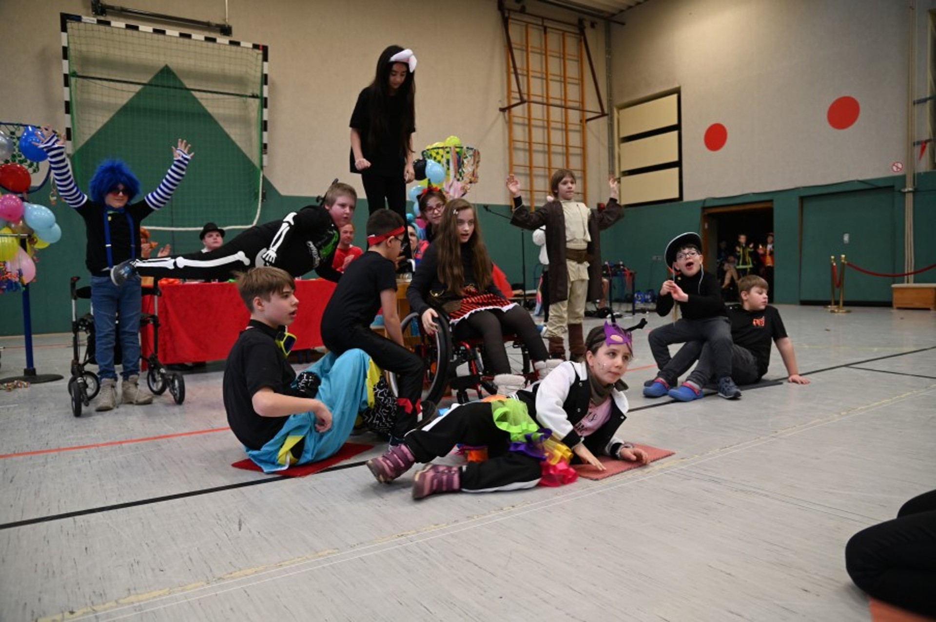 In einer Turnhalle formen verkleidete Kinder mit ihren Körpern eine Pyramide.