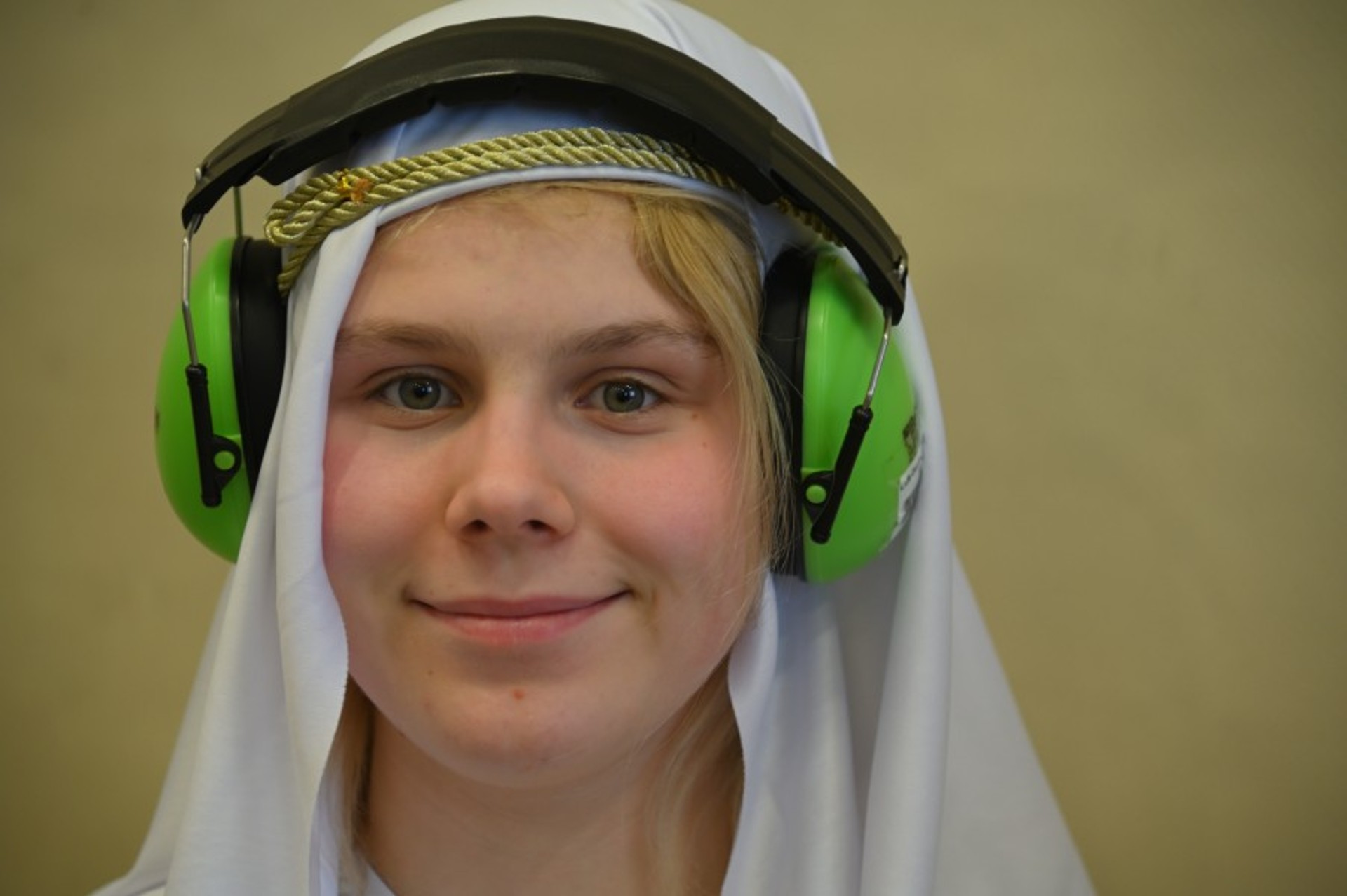 Porträtfoto eines als Scheich verkleideten Kindes. Es trägt grüne Schallschutz-Kopfhörer.
